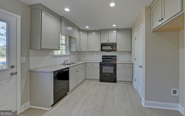 kitchen with baseboards, gray cabinets, a sink, backsplash, and black appliances