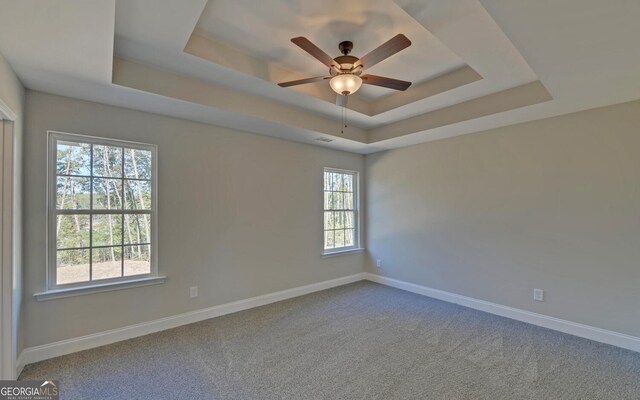 empty room featuring visible vents, a raised ceiling, plenty of natural light, and ceiling fan