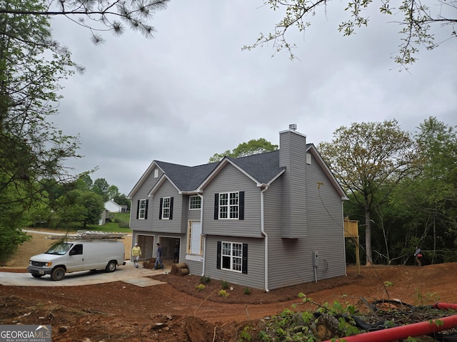 view of front of home with an attached garage, a chimney, and concrete driveway