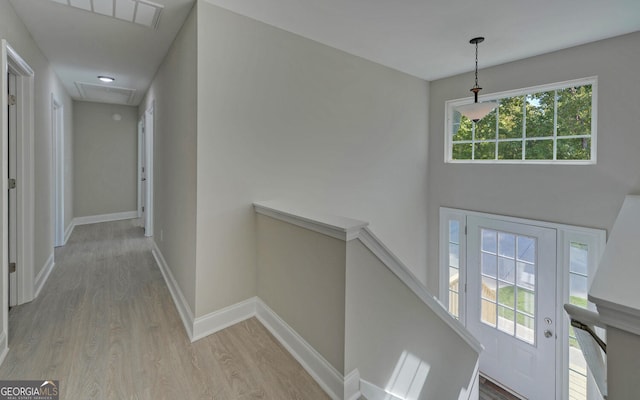 corridor with baseboards, an upstairs landing, wood finished floors, and attic access