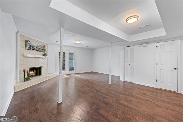 basement with visible vents, baseboards, a brick fireplace, and wood finished floors