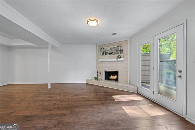 unfurnished living room with crown molding, a brick fireplace, wood finished floors, and baseboards