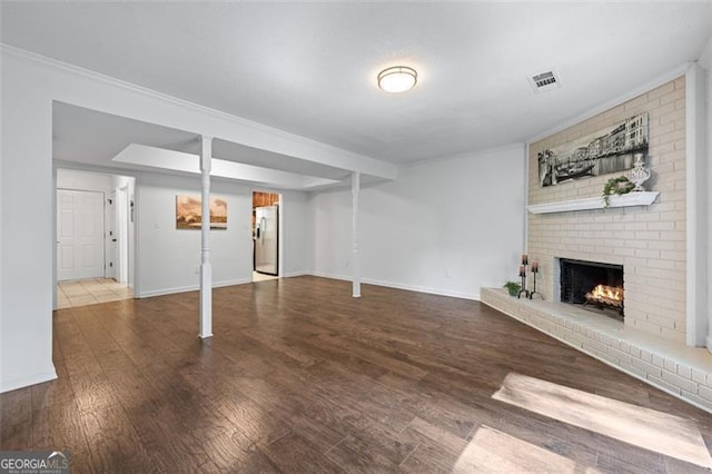 basement with a fireplace, visible vents, stainless steel refrigerator with ice dispenser, wood finished floors, and baseboards
