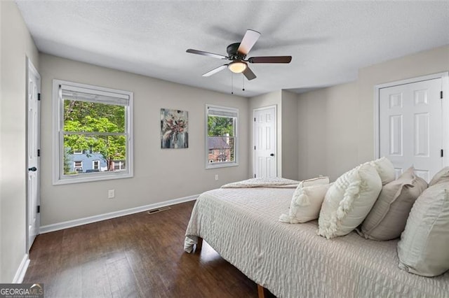 bedroom featuring visible vents, baseboards, multiple windows, and wood finished floors