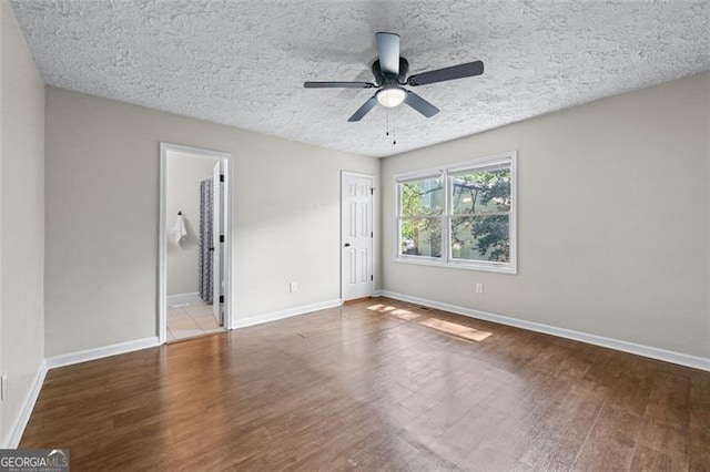 unfurnished bedroom featuring a closet, baseboards, ceiling fan, a textured ceiling, and wood finished floors