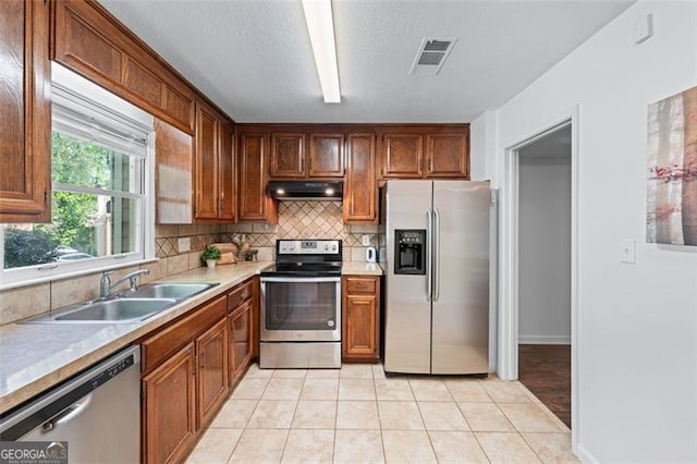 kitchen with visible vents, a sink, appliances with stainless steel finishes, under cabinet range hood, and decorative backsplash