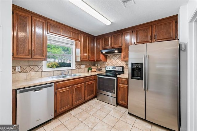 kitchen with under cabinet range hood, light countertops, a sink, and appliances with stainless steel finishes