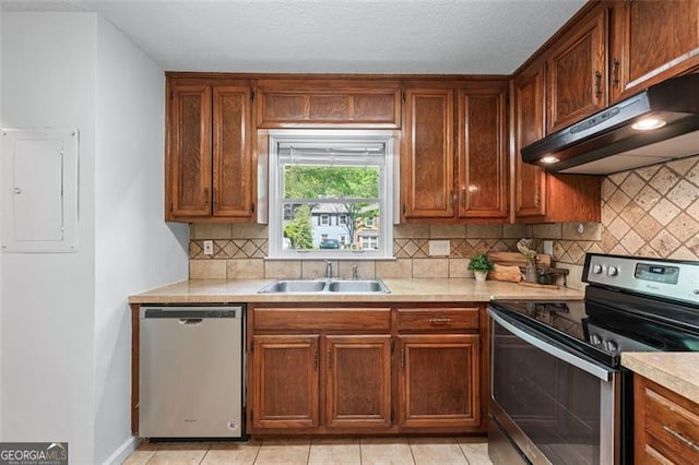 kitchen featuring electric panel, light countertops, under cabinet range hood, stainless steel appliances, and a sink