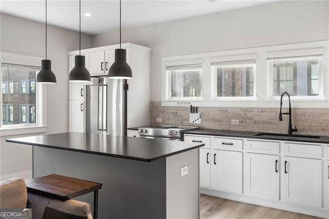 kitchen with tasteful backsplash, a center island, a sink, dark countertops, and stainless steel appliances