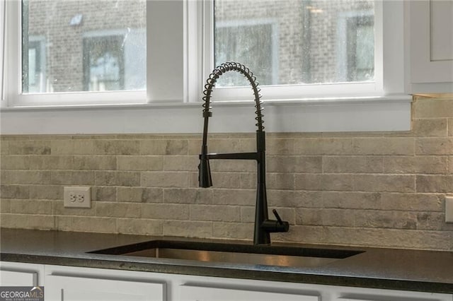 details with decorative backsplash, a sink, white cabinets, and dark countertops
