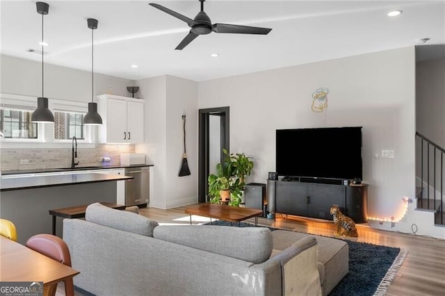 living area with ceiling fan, light wood finished floors, recessed lighting, and stairs