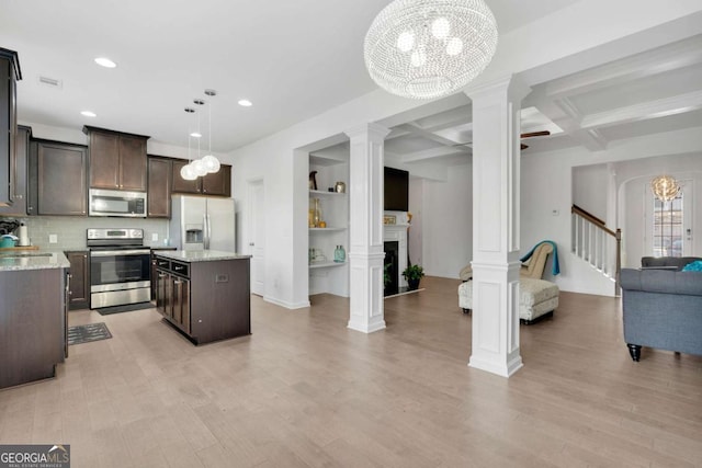 kitchen with open floor plan, a chandelier, a fireplace, dark brown cabinets, and stainless steel appliances