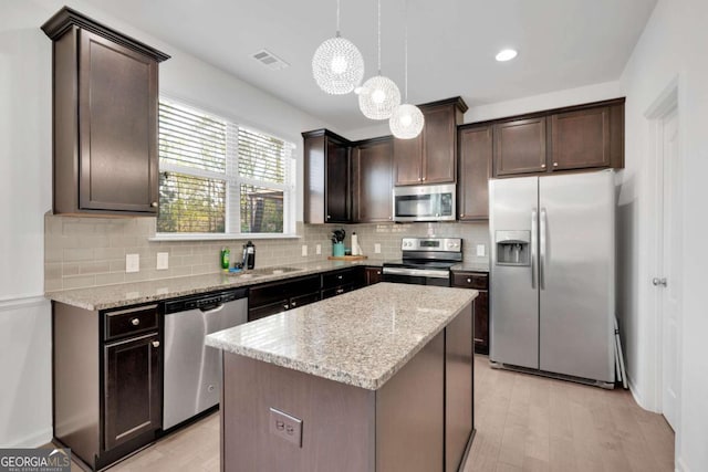 kitchen with visible vents, appliances with stainless steel finishes, light stone counters, and dark brown cabinetry