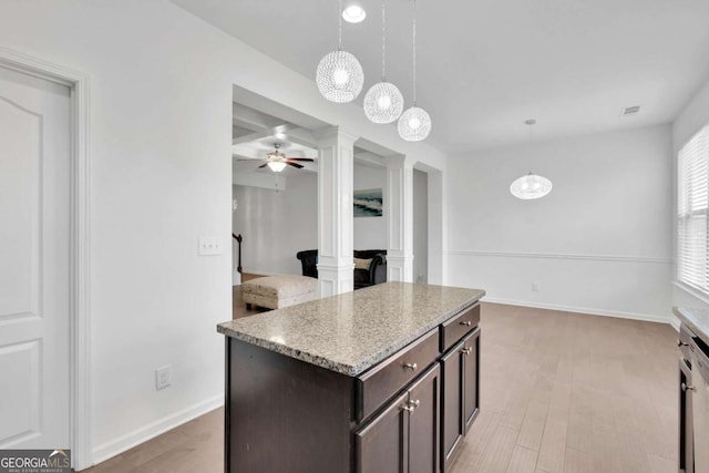 kitchen with dark brown cabinetry, baseboards, light stone countertops, decorative columns, and hanging light fixtures