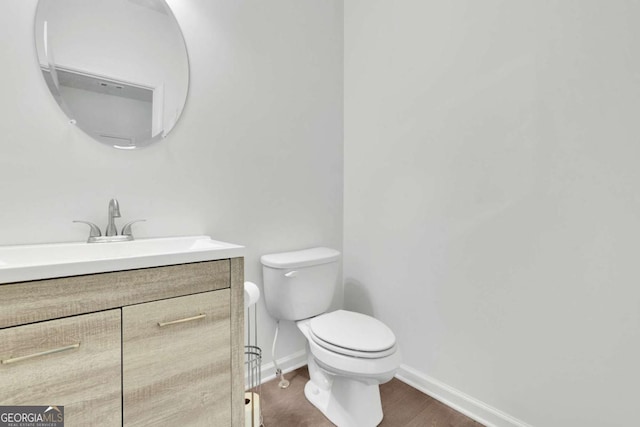 bathroom featuring toilet, baseboards, vanity, and wood finished floors