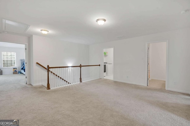 carpeted empty room with baseboards and attic access