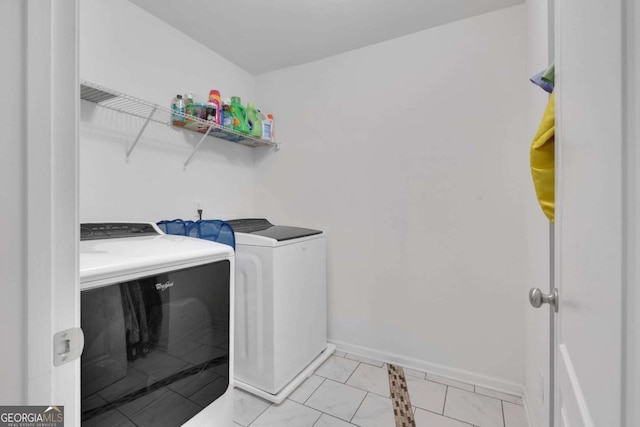 laundry room featuring light tile patterned floors, separate washer and dryer, laundry area, and baseboards