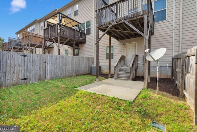 rear view of house with central air condition unit, a fenced backyard, and a lawn