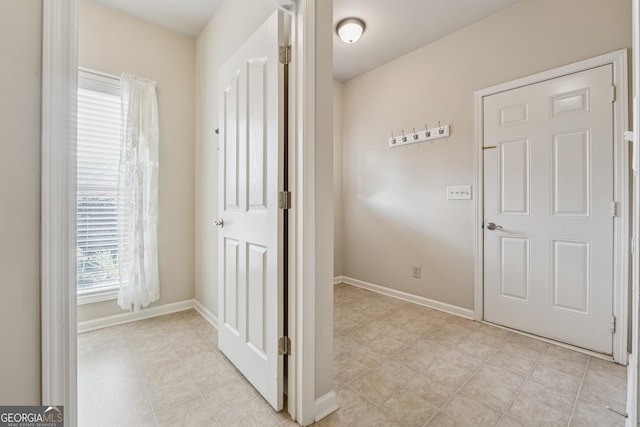 corridor with light tile patterned floors and baseboards