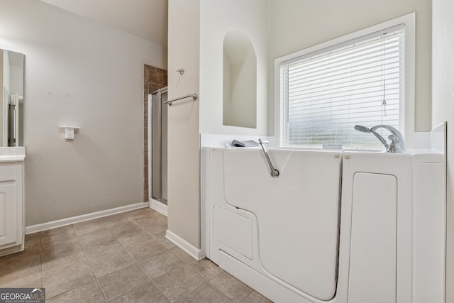 bathroom featuring a shower with shower door and baseboards