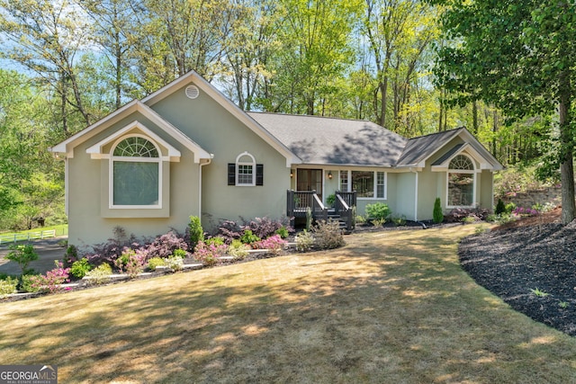 ranch-style home with a shingled roof, stucco siding, and a front lawn