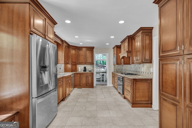 kitchen featuring appliances with stainless steel finishes, brown cabinets, recessed lighting, light stone countertops, and decorative backsplash