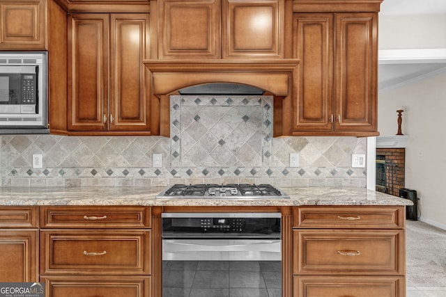 kitchen with brown cabinets, light stone counters, and stainless steel appliances