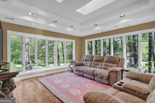 living area with recessed lighting, a raised ceiling, visible vents, a skylight, and wood finished floors