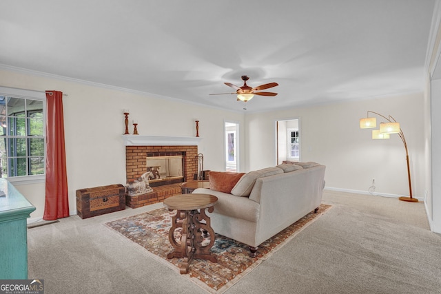 carpeted living room with ornamental molding, ceiling fan, a brick fireplace, and baseboards