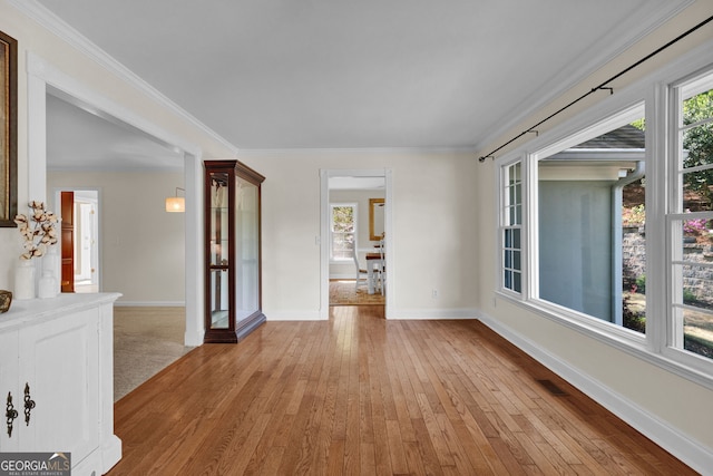 spare room with light wood-style floors, baseboards, ornamental molding, and visible vents