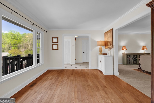 spare room featuring light wood-style flooring, baseboards, ornamental molding, and visible vents