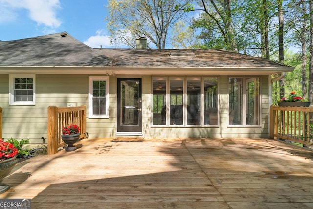 exterior space featuring roof with shingles, a wooden deck, and a chimney
