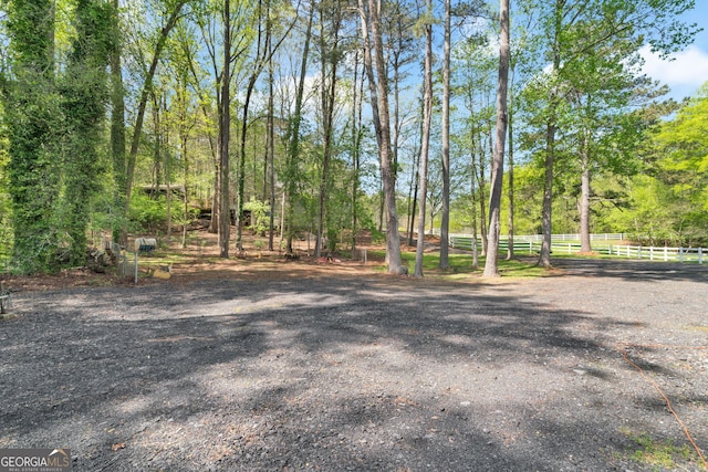 view of yard with a wooded view and fence