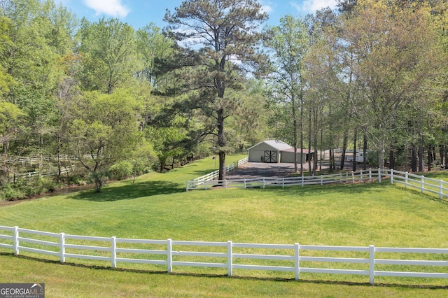 view of yard featuring a rural view, fence, an outbuilding, and a pole building