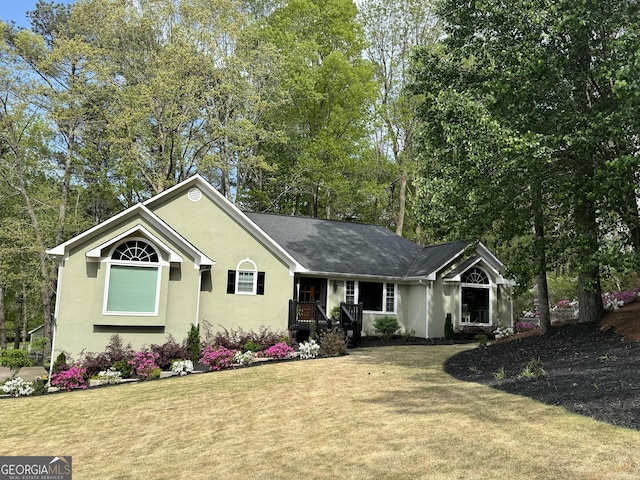 ranch-style house featuring roof with shingles, stucco siding, and a front lawn
