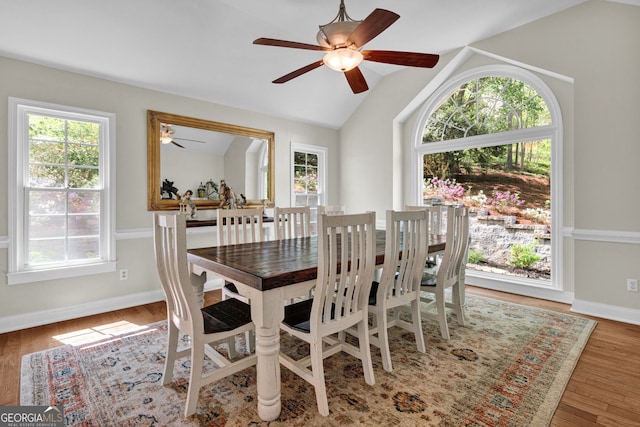 dining room with wood finished floors, ceiling fan, baseboards, and vaulted ceiling