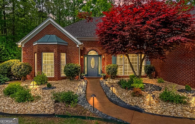 view of front of home featuring brick siding and roof with shingles