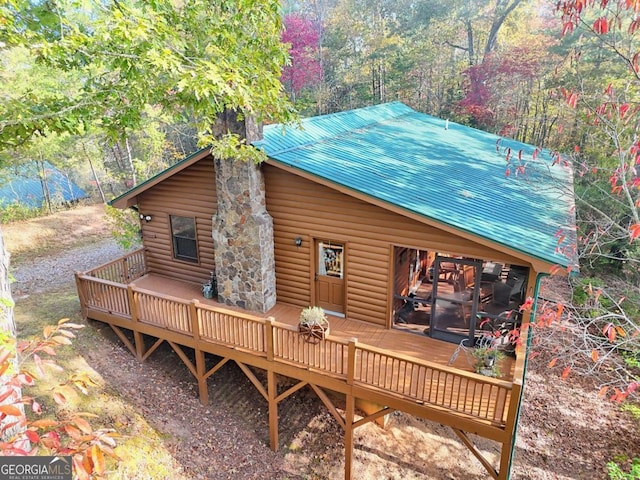 rear view of property featuring a deck, metal roof, and faux log siding