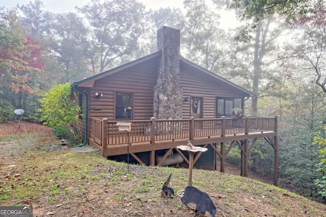 back of property featuring a chimney and a wooden deck
