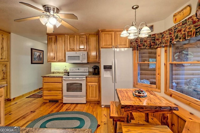 kitchen featuring white appliances, light wood-style flooring, ceiling fan with notable chandelier, and pendant lighting