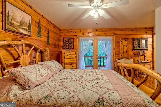 bedroom with wood walls, a ceiling fan, a textured ceiling, french doors, and access to exterior
