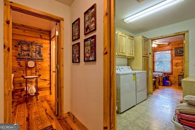 laundry area with cabinet space, washing machine and dryer, light floors, and wooden walls