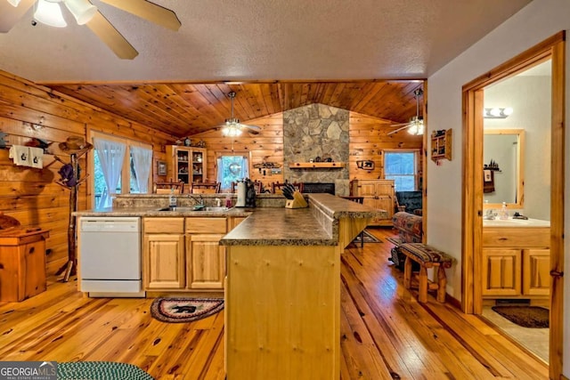 kitchen with open floor plan, wood walls, dishwasher, and a ceiling fan