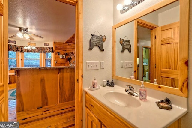 bathroom featuring a ceiling fan, vanity, and a textured wall