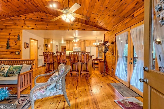dining area featuring ceiling fan with notable chandelier, wood ceiling, light wood-style floors, and lofted ceiling