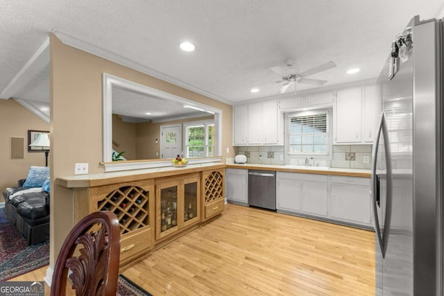 kitchen with light wood-style floors, light countertops, ornamental molding, and appliances with stainless steel finishes