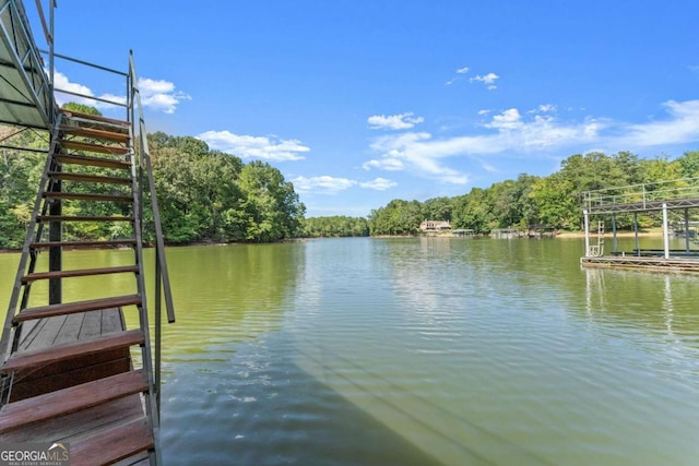 dock area featuring a water view, stairway, and a view of trees