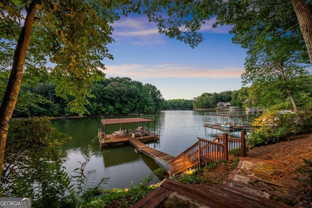 view of dock with boat lift, a forest view, and a water view