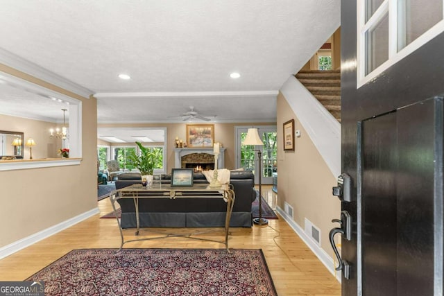 living area featuring a lit fireplace, light wood-style floors, baseboards, and visible vents