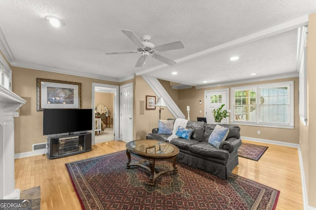 living room with crown molding, visible vents, a ceiling fan, and wood finished floors